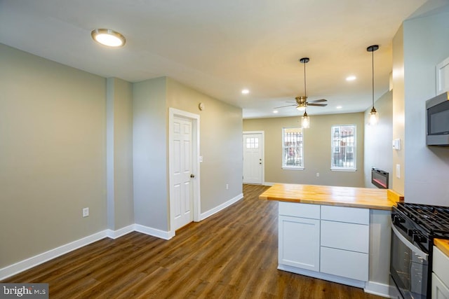 kitchen with dark wood-type flooring, butcher block counters, gas stove, hanging light fixtures, and white cabinets