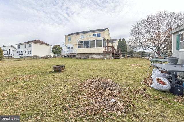 view of yard with a wooden deck, a fire pit, and a sunroom