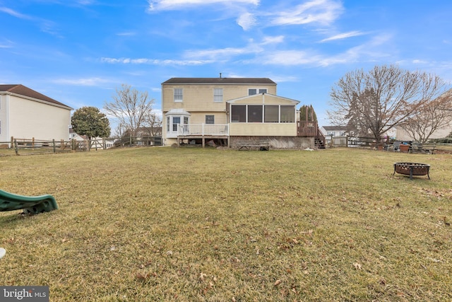 rear view of property with a wooden deck, a lawn, a sunroom, and an outdoor fire pit