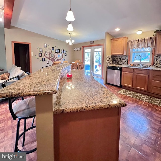 kitchen with sink, a breakfast bar area, tasteful backsplash, dishwasher, and pendant lighting