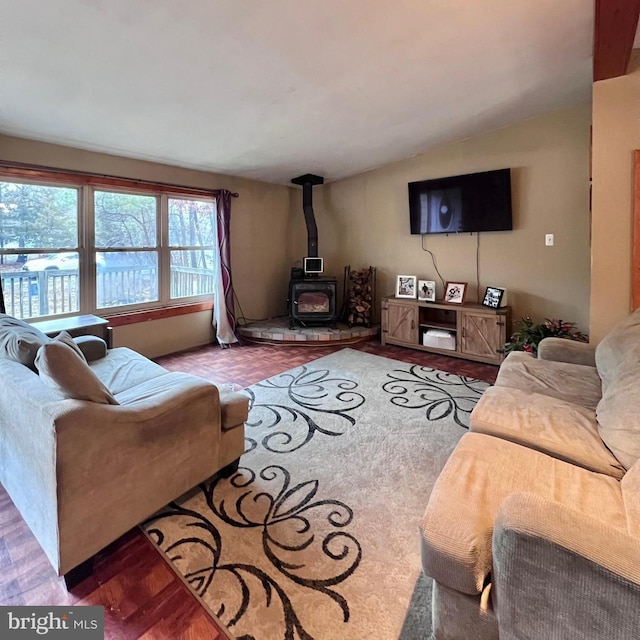 living room featuring hardwood / wood-style flooring, vaulted ceiling, and a wood stove