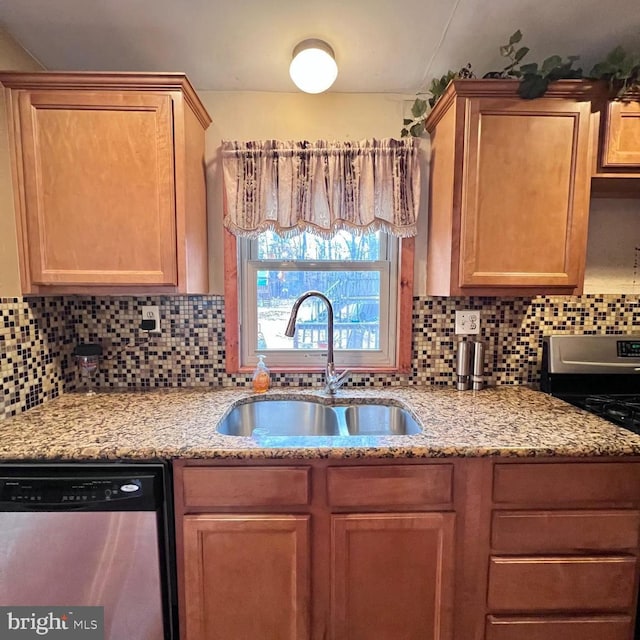 kitchen featuring light stone counters, appliances with stainless steel finishes, sink, and decorative backsplash