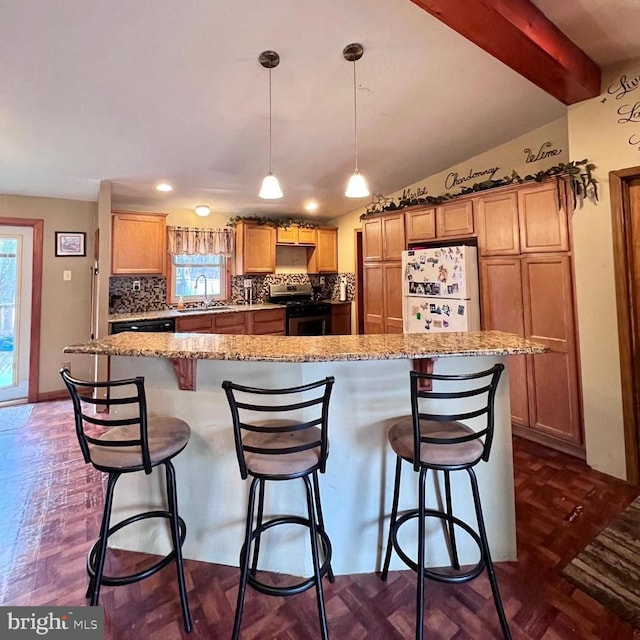 kitchen featuring hanging light fixtures, a kitchen breakfast bar, a kitchen island, gas range, and white fridge