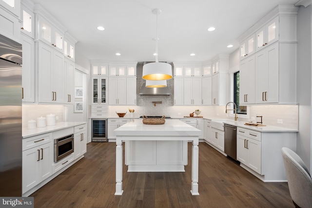 kitchen featuring beverage cooler, a center island, built in appliances, and white cabinets