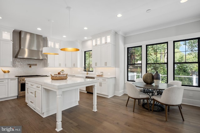 kitchen with white cabinetry, appliances with stainless steel finishes, a center island, and wall chimney exhaust hood