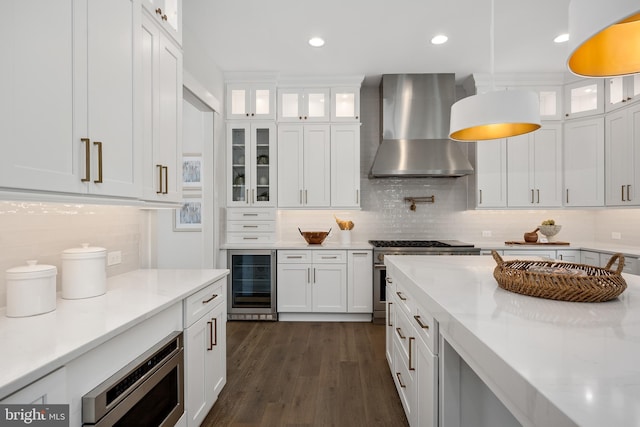 kitchen featuring white cabinetry, wall chimney range hood, beverage cooler, and appliances with stainless steel finishes