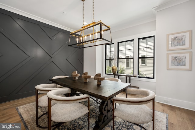 dining space with hardwood / wood-style flooring, ornamental molding, and a notable chandelier