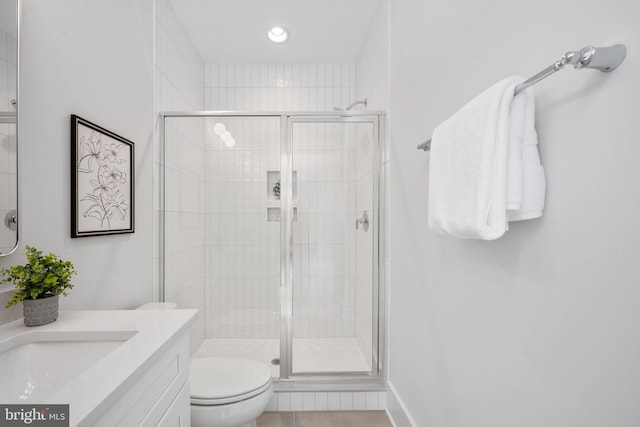 bathroom with vanity, toilet, and a shower with door