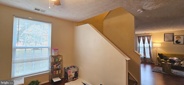 staircase featuring hardwood / wood-style floors, a textured ceiling, and ceiling fan