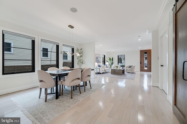 dining area featuring a barn door and light hardwood / wood-style flooring