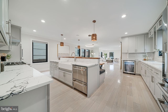 kitchen with pendant lighting, a large island, sink, gray cabinets, and beverage cooler