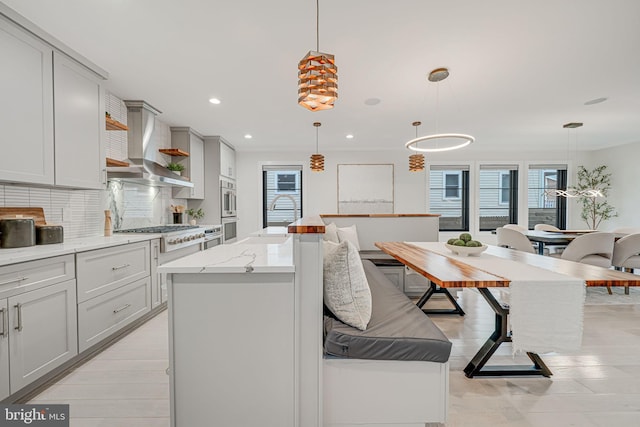 kitchen featuring decorative light fixtures, a center island, and wall chimney range hood