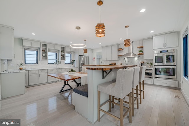 kitchen with white cabinetry, decorative backsplash, hanging light fixtures, a center island, and stainless steel appliances