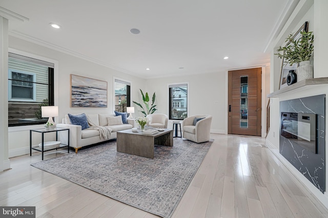 living room featuring crown molding, a high end fireplace, and light hardwood / wood-style floors