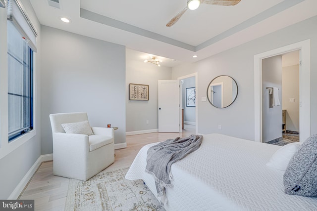 bedroom with a tray ceiling and light hardwood / wood-style floors