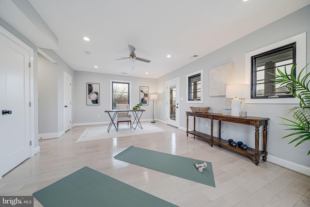 workout room with ceiling fan and light wood-type flooring