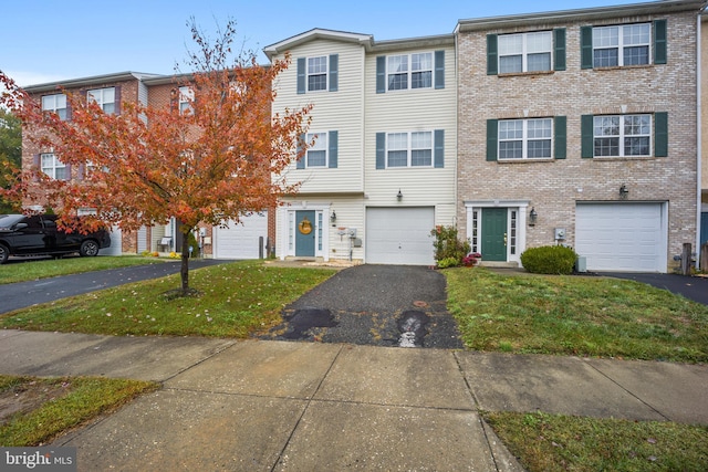 view of property with a garage, a front yard, brick siding, and driveway