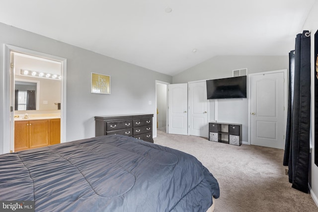 carpeted bedroom featuring lofted ceiling, visible vents, a sink, and ensuite bathroom