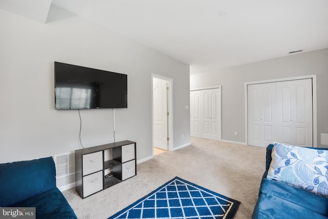 bedroom featuring visible vents, baseboards, light colored carpet, and multiple closets