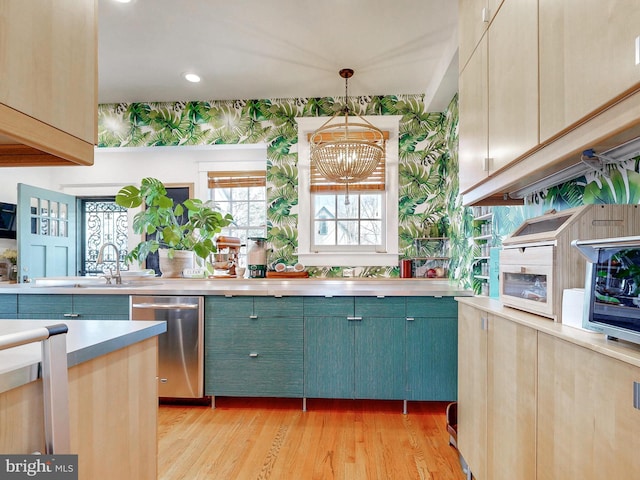 kitchen featuring light brown cabinetry, decorative light fixtures, stainless steel dishwasher, a chandelier, and light wood-type flooring