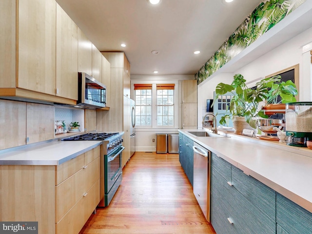 kitchen with sink, appliances with stainless steel finishes, backsplash, light hardwood / wood-style floors, and light brown cabinetry