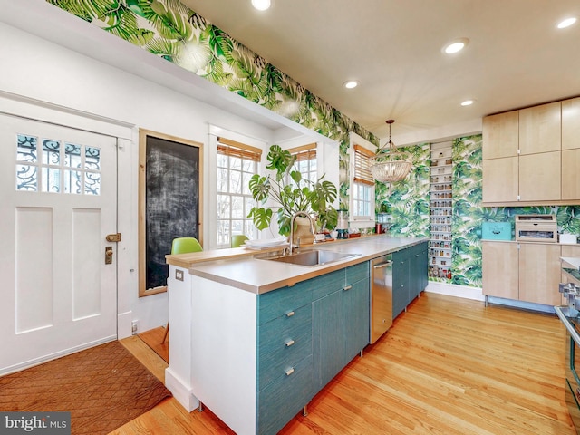 kitchen featuring stainless steel appliances, sink, pendant lighting, and light hardwood / wood-style floors