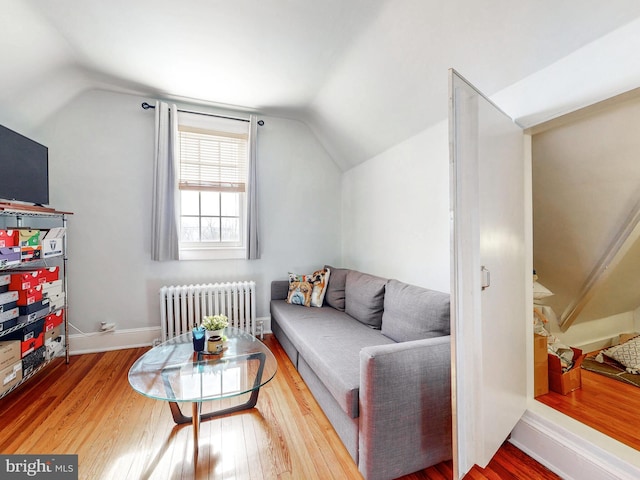 living room with hardwood / wood-style floors, radiator heating unit, and vaulted ceiling