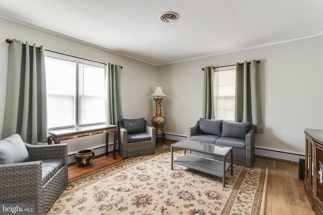 sitting room featuring ornamental molding, a baseboard heating unit, and dark wood-type flooring