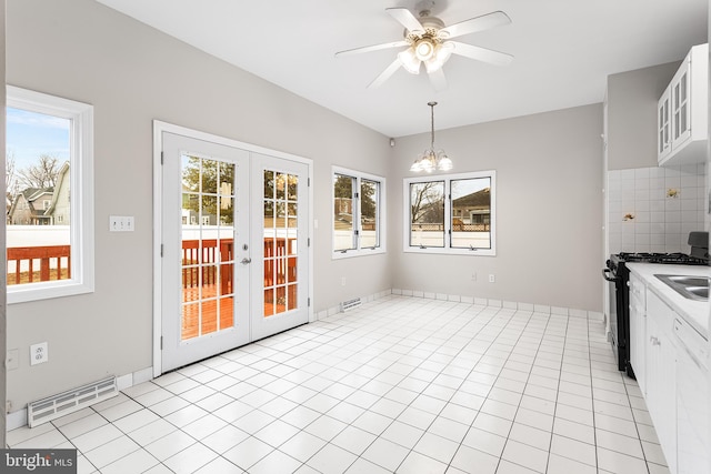 kitchen with decorative light fixtures, black gas stove, a wealth of natural light, decorative backsplash, and white cabinets