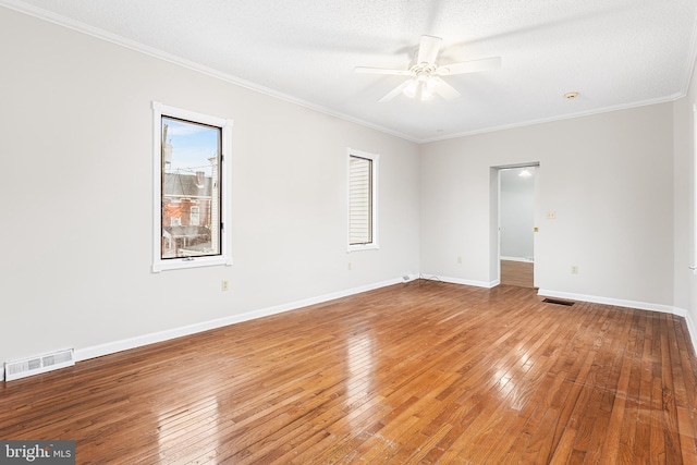 empty room with hardwood / wood-style flooring, ornamental molding, ceiling fan, and a textured ceiling