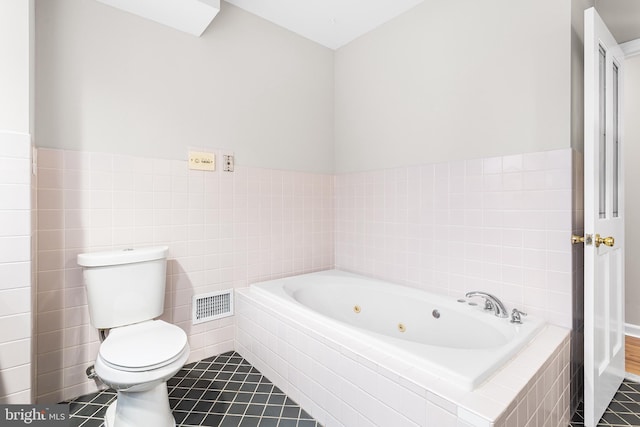 bathroom with a relaxing tiled tub, tile patterned floors, toilet, and tile walls