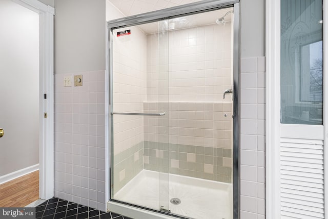 bathroom with tile walls, an enclosed shower, and tile patterned floors