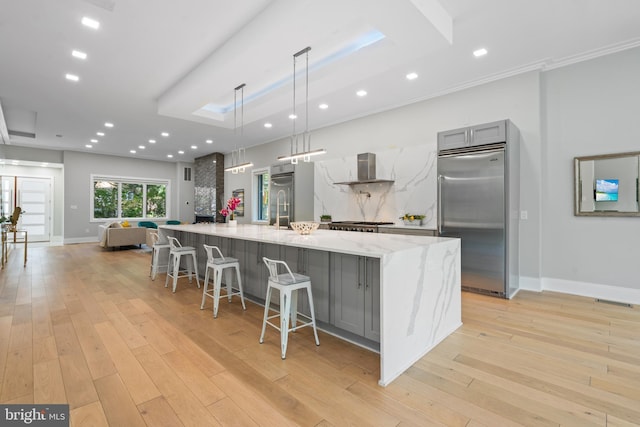 kitchen featuring gray cabinets, appliances with stainless steel finishes, hanging light fixtures, light stone countertops, and a spacious island