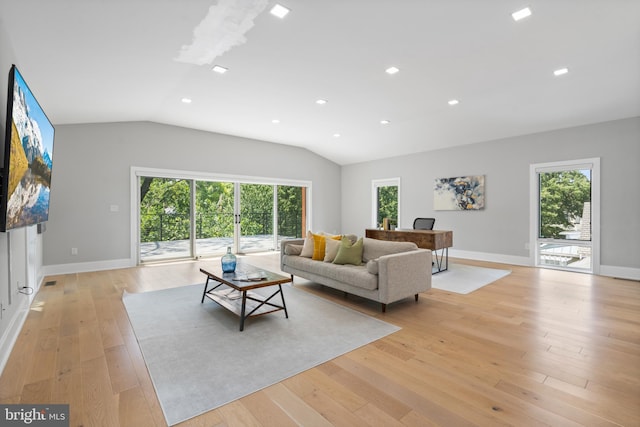 living room with vaulted ceiling, a healthy amount of sunlight, and light hardwood / wood-style flooring