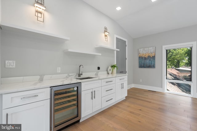 kitchen with lofted ceiling, sink, white cabinets, beverage cooler, and light wood-type flooring