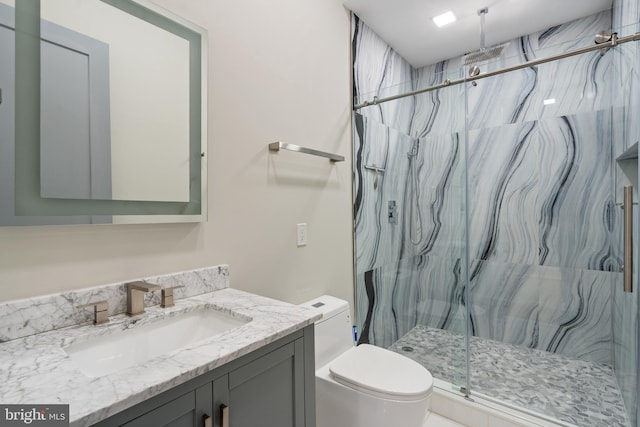 bathroom featuring vanity, a shower with shower door, and toilet