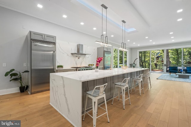 kitchen with pendant lighting, light stone counters, a large island with sink, and stainless steel built in fridge