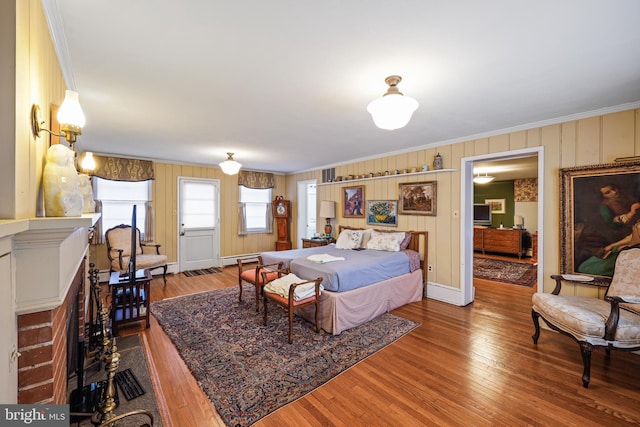 bedroom featuring crown molding, wood-type flooring, and a baseboard heating unit