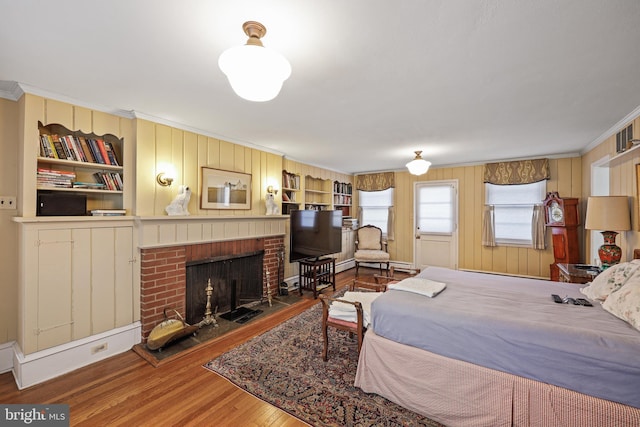 bedroom with hardwood / wood-style flooring, crown molding, and a fireplace