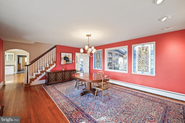 dining space featuring a baseboard heating unit, hardwood / wood-style floors, and an inviting chandelier