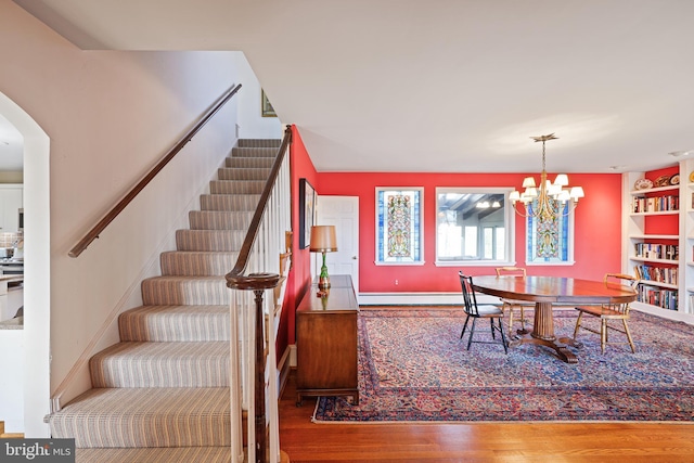 dining room with hardwood / wood-style flooring, an inviting chandelier, and a baseboard heating unit