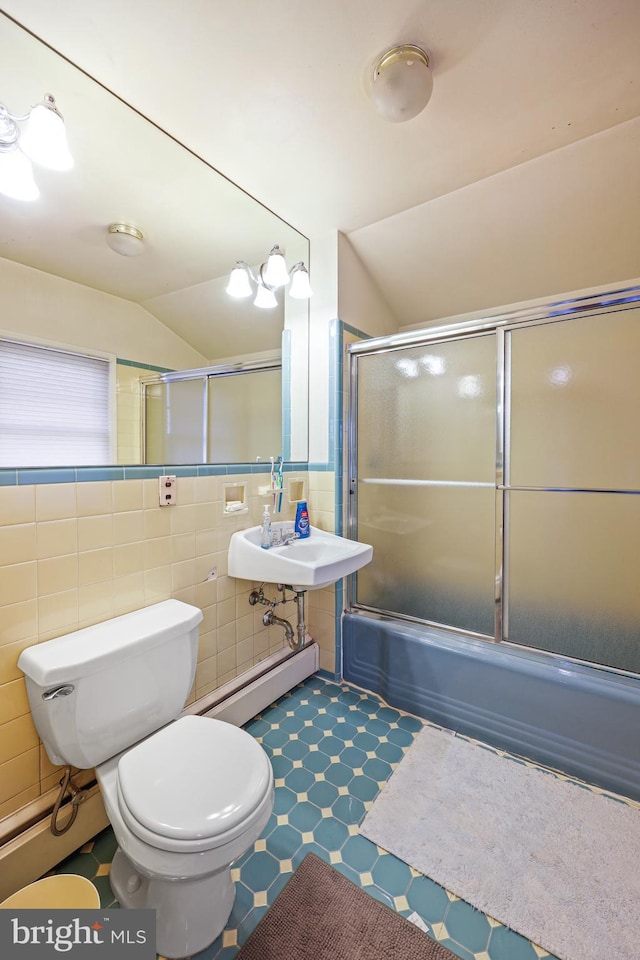 full bathroom with lofted ceiling, tile walls, bath / shower combo with glass door, a baseboard radiator, and toilet