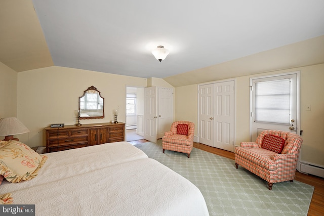 bedroom with hardwood / wood-style flooring, vaulted ceiling, and baseboard heating