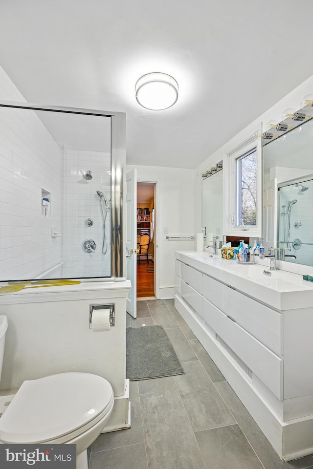 bathroom with tile patterned floors, vanity, toilet, and a shower with door