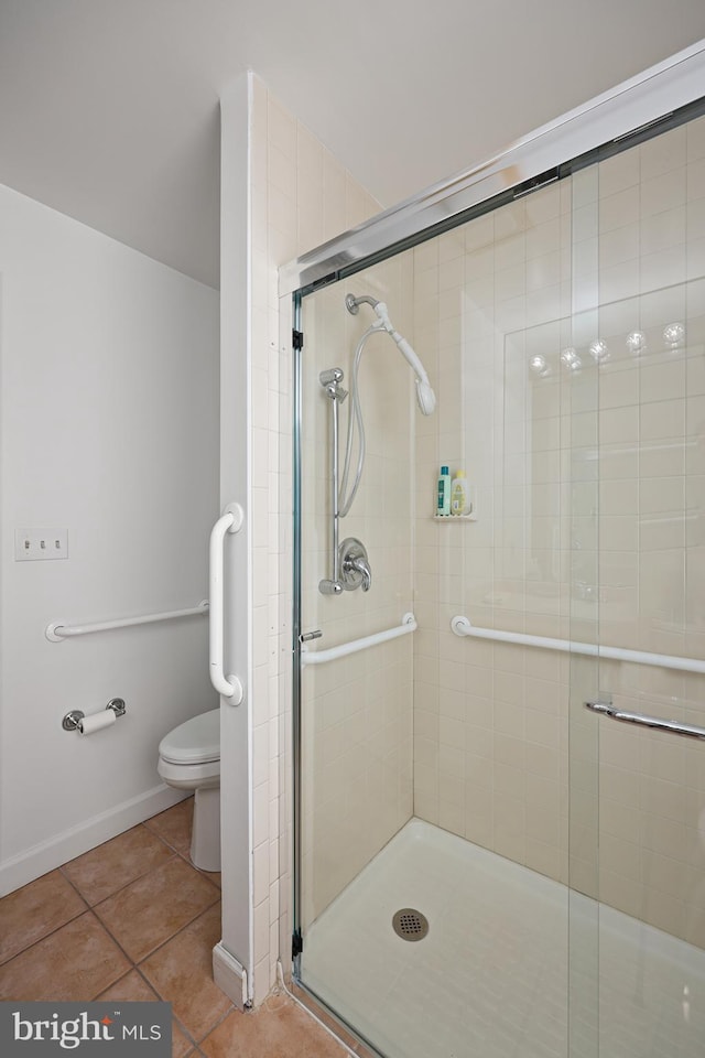 bathroom featuring a shower with shower door, tile patterned floors, and toilet