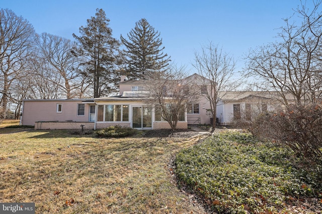 rear view of house with a sunroom and a lawn