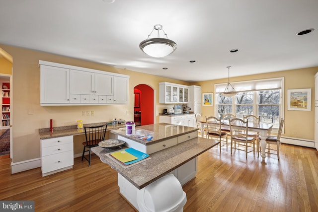 kitchen with a kitchen bar, light wood-type flooring, a kitchen island, and white cabinets