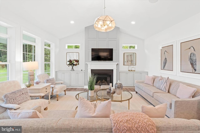 living room featuring lofted ceiling, a large fireplace, a chandelier, and light hardwood / wood-style floors