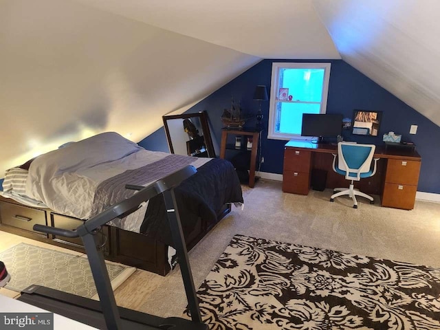 bedroom with vaulted ceiling, light colored carpet, and baseboards