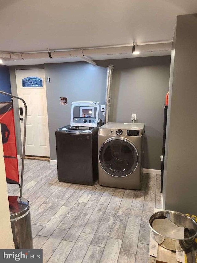 clothes washing area with light wood-type flooring, laundry area, washer and clothes dryer, and baseboards